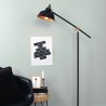 Industrijska podna lampa Steinhauer Mexlite Nové u mat crnoj boji sa zlatnom unutrašnjošću abažura pored radnog stola
